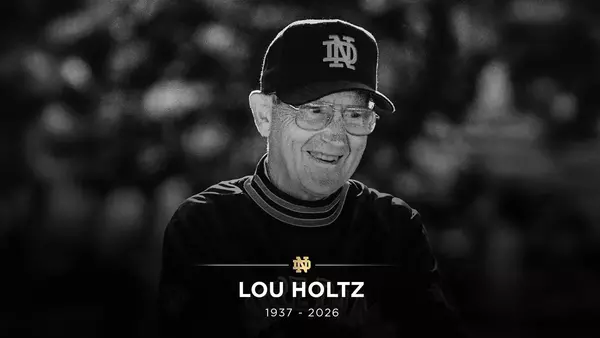 A smiling Lou Holtz in black and white, wearing a Notre Dame cap and glasses. Text: LOU HOLTZ, 1937 - 2026.